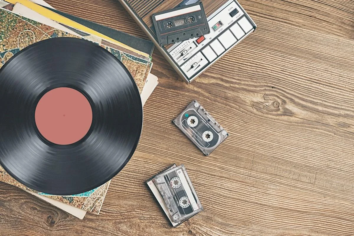Discos de vinil e fitas cassete sobre uma mesa de madeira